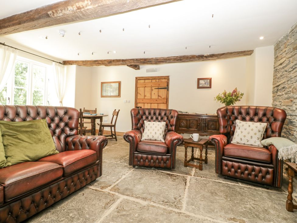 A living room with leather sofas and a wooden table at Evenjobb Court Farmhouse near Presteigne