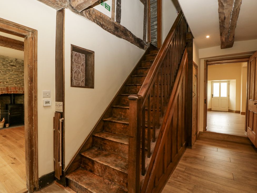 A hallway with a staircase and door at Evenjobb Court Farmhouse near Presteigne
