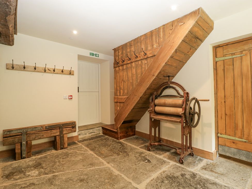 A hallway with a staircase and coatrack at Evenjobb Court Farmhouse in Evenjobb near Presteigne