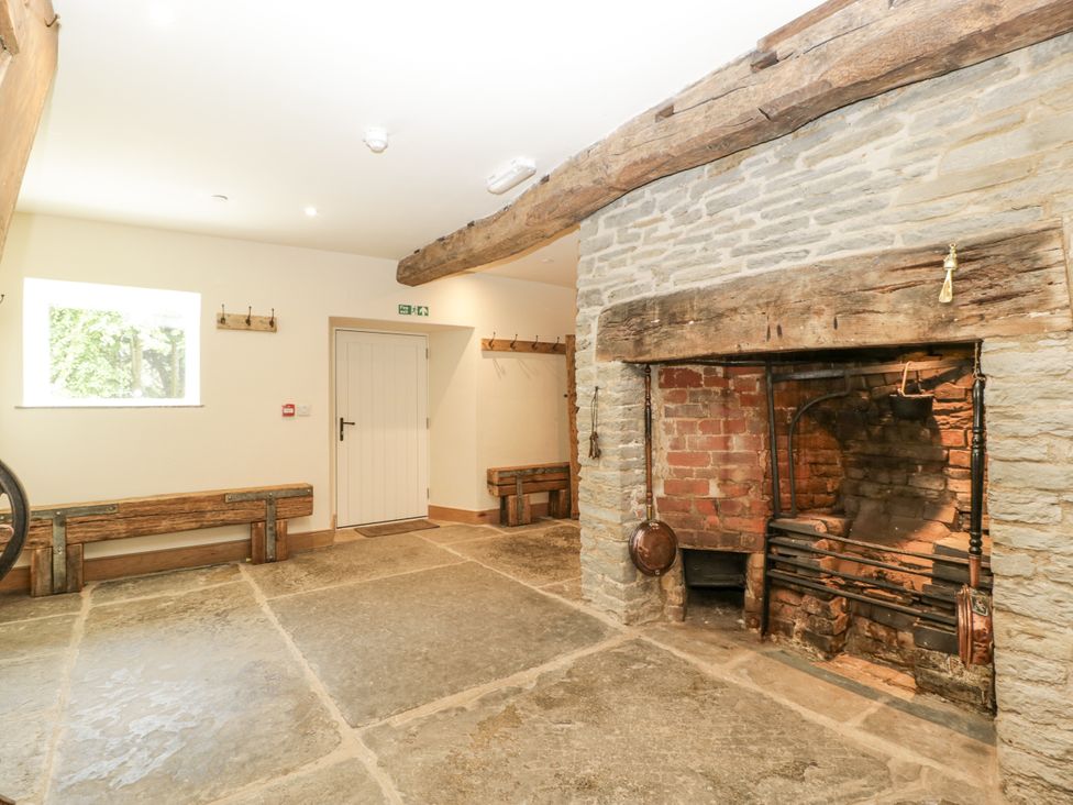 An indoor area with a fireplace, benches and a window at Evenjobb Court Farmhouse in Evenjobb near Presteigne