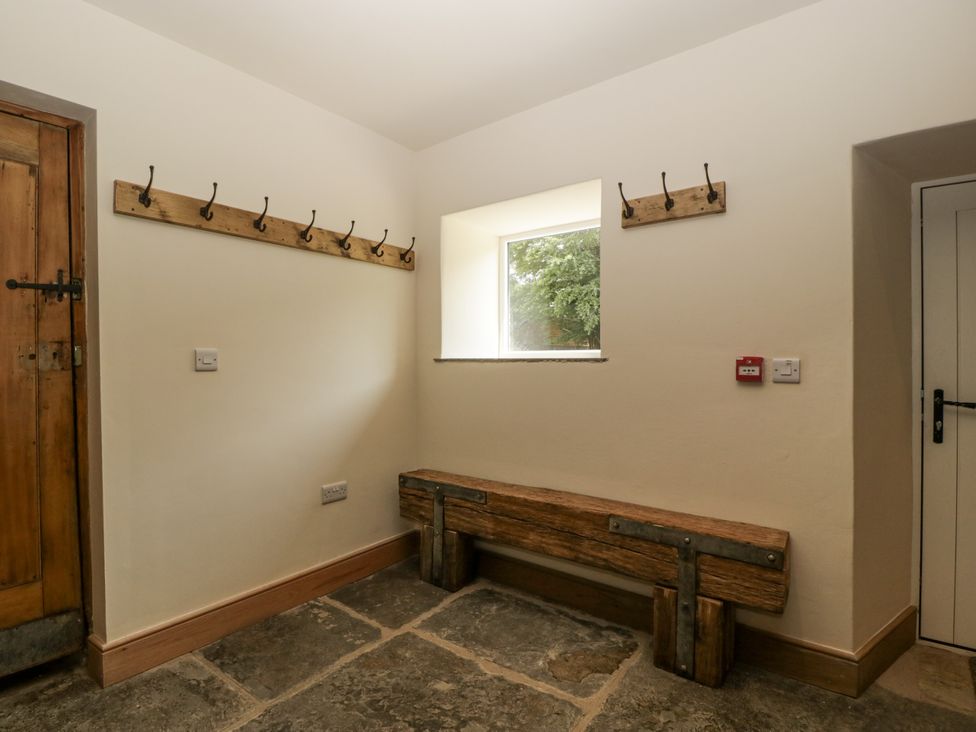 A hallway with coat hooks and a bench at Evenjobb Court Farmhouse Evenjobb near Presteigne