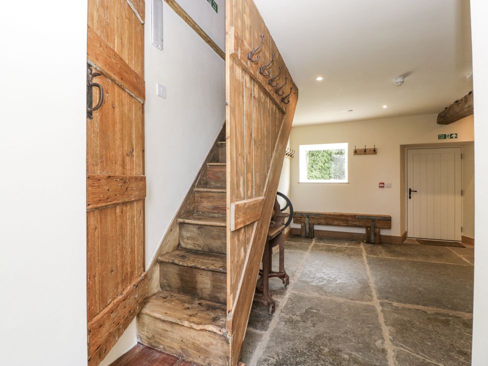 A hallway with stairs and a wooden bench at Evenjobb Court Farmhouse near Presteigne