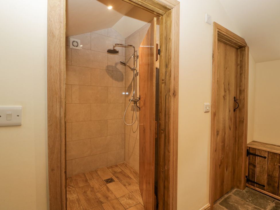 A shower area with tiles and wooden elements at Evenjobb Court Farmhouse near Presteigne
