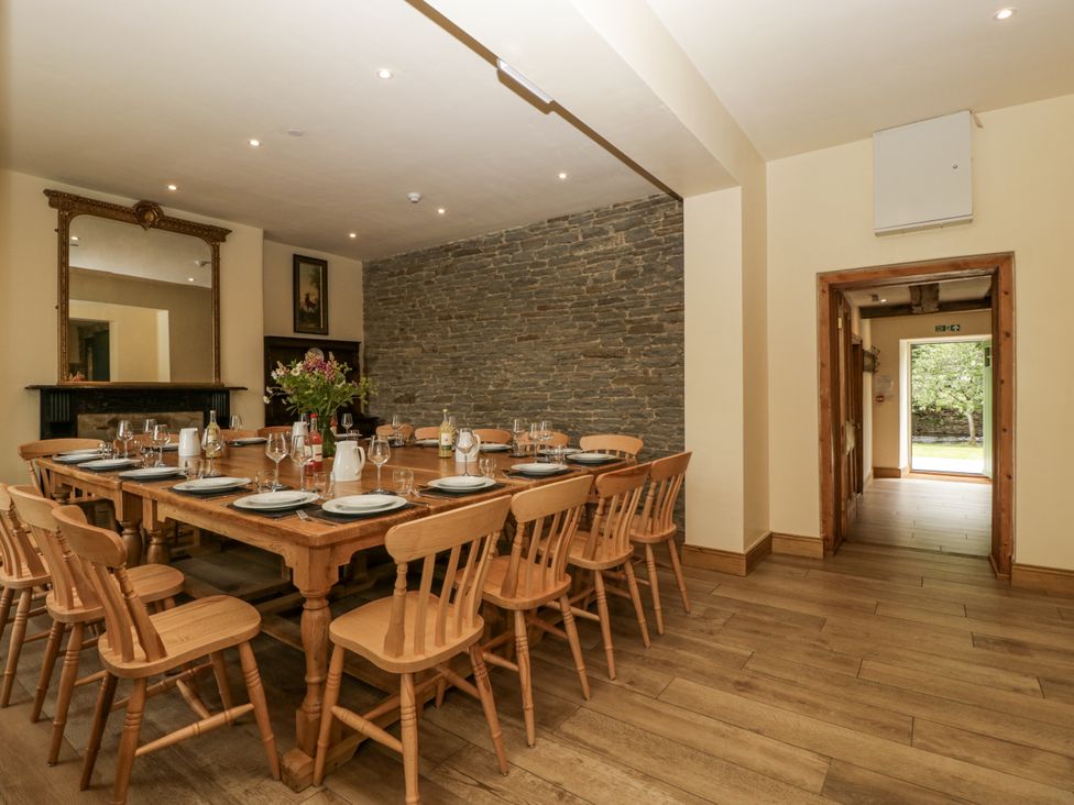 A dining room with a long table and chairs at Evenjobb Court Farmhouse near Presteigne