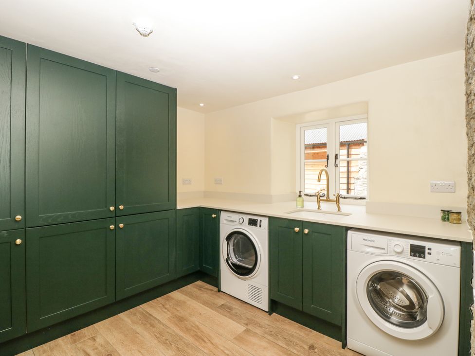 A laundry room with washing machines and a sink at Evenjobb Court Farmhouse near Presteigne