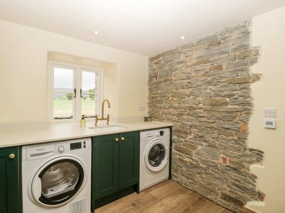 A laundry room with washing machines and a sink at Evenjobb Court Farmhouse near Presteigne