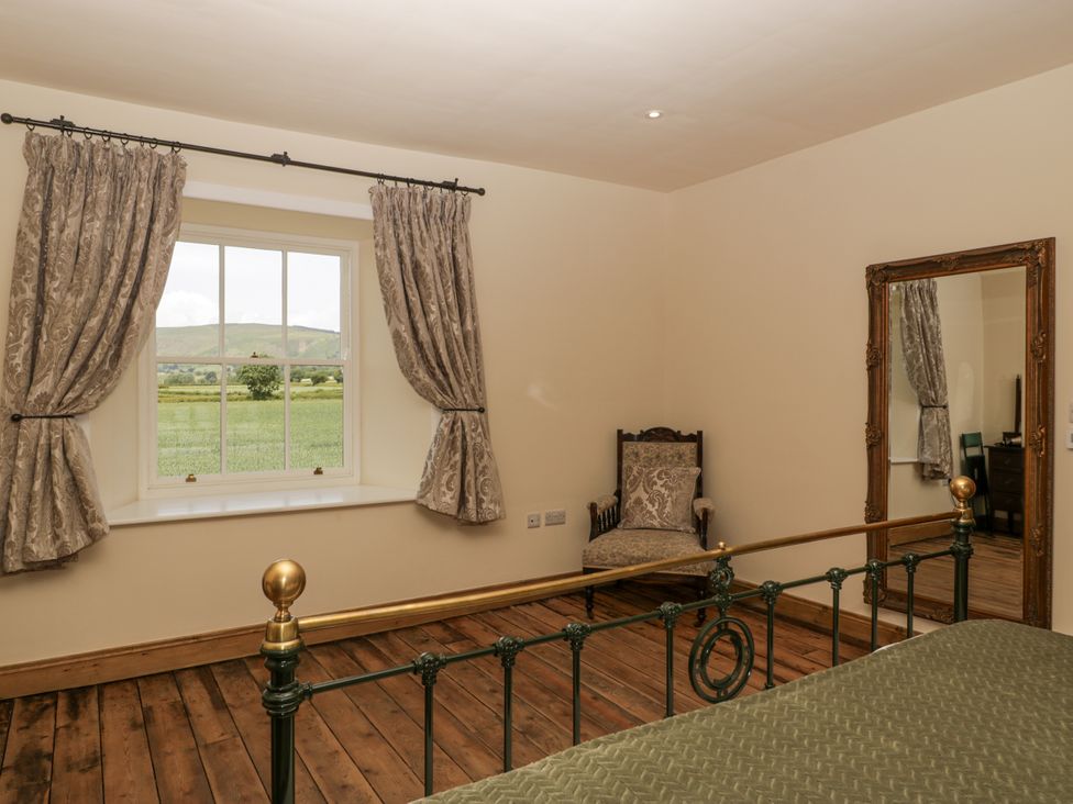 A bedroom with a bed and a chair at Evenjobb Court Farmhouse near Presteigne