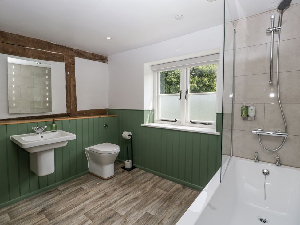 A bathroom with a bathtub, sink, and toilet at Evenjobb Court Farmhouse near Presteigne
