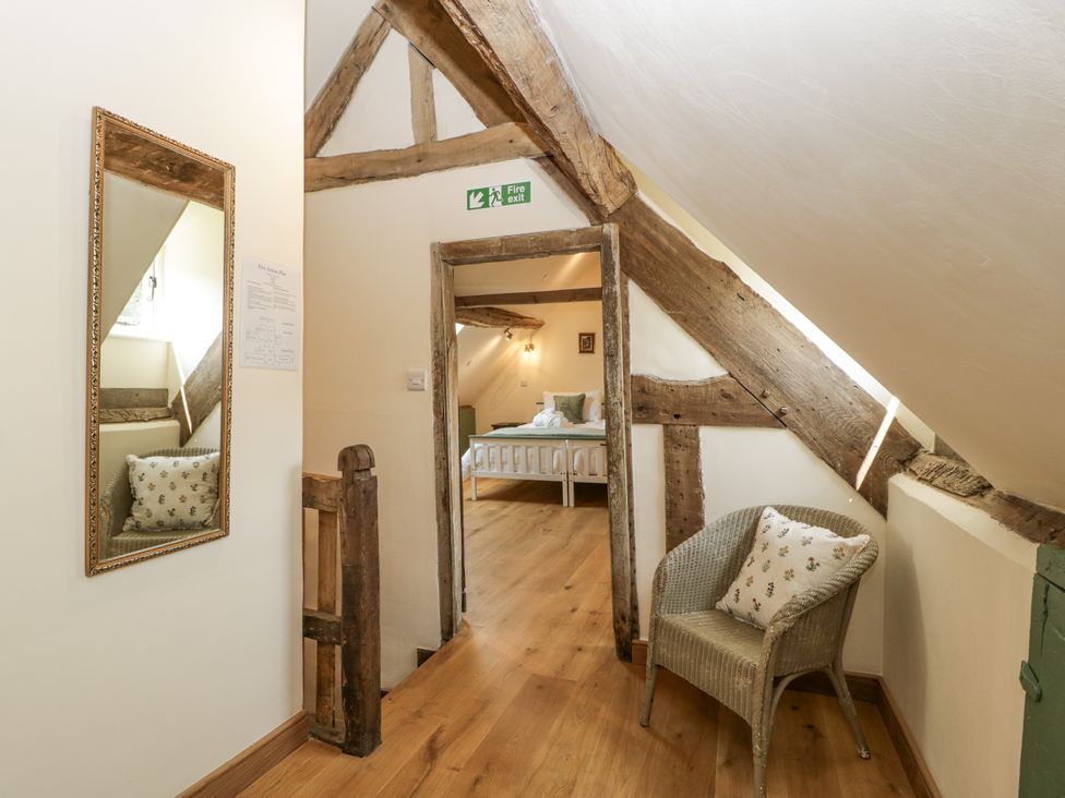 A hallway with a mirror and an open door at Evenjobb Court Farmhouse near Presteigne
