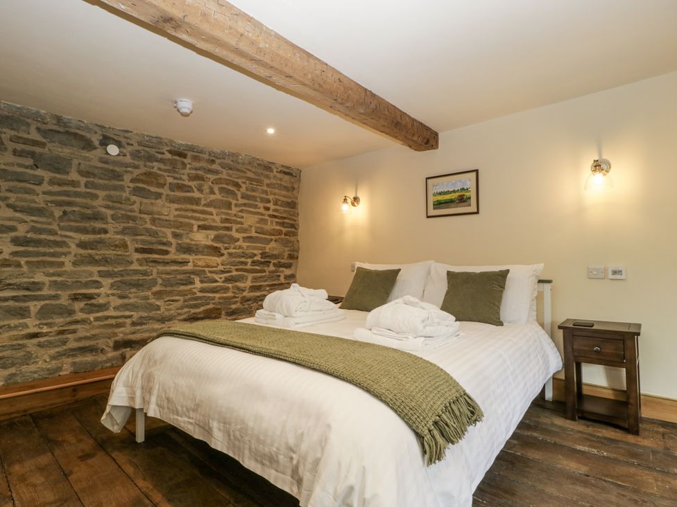 A bedroom with a bed and nightstand at Evenjobb Court Farmhouse near Presteigne