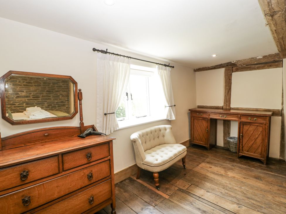 A bedroom with a dresser and mirror at Evenjobb Court Farmhouse near Presteigne