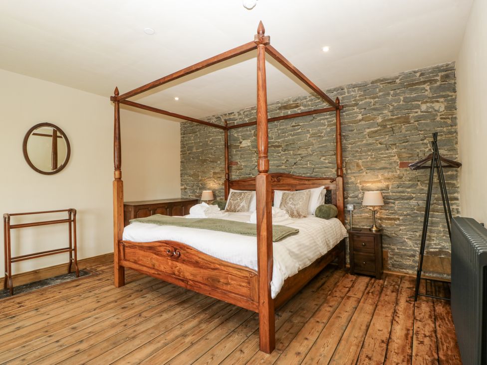 A bedroom with a four-poster bed and wooden furniture at Evenjobb Court Farmhouse near Presteigne