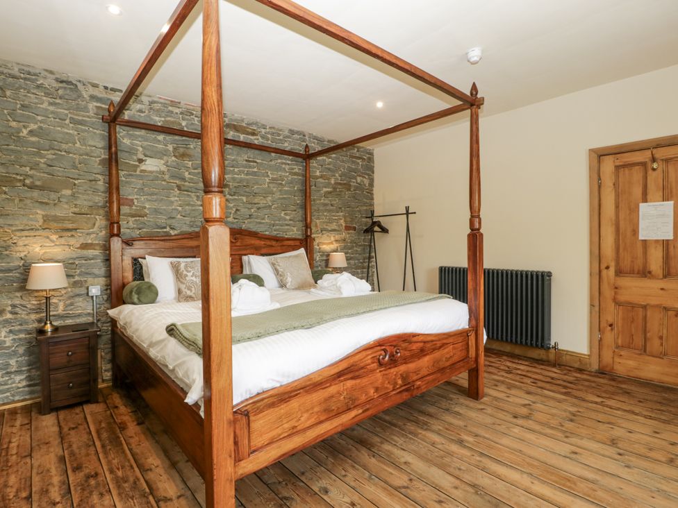 A bedroom with a four-poster bed and wooden flooring at Evenjobb Court Farmhouse near Presteigne