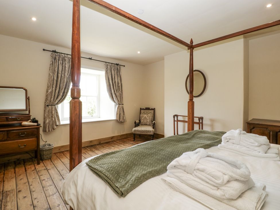 A bedroom featuring a four-poster bed and dressing table at Evenjobb Court Farmhouse near Presteigne