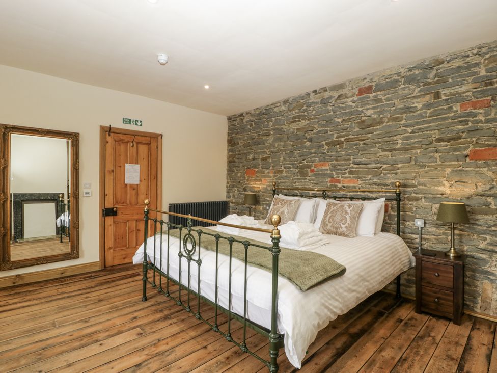 A bedroom with a bed and a mirror at Evenjobb Court Farmhouse Evenjobb near Presteigne