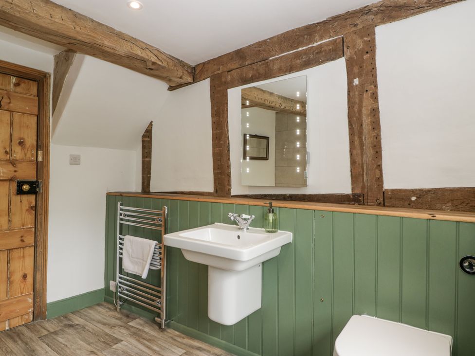 A bathroom with a sink, toilet, and towel rail at Evenjobb Court Farmhouse near Presteigne