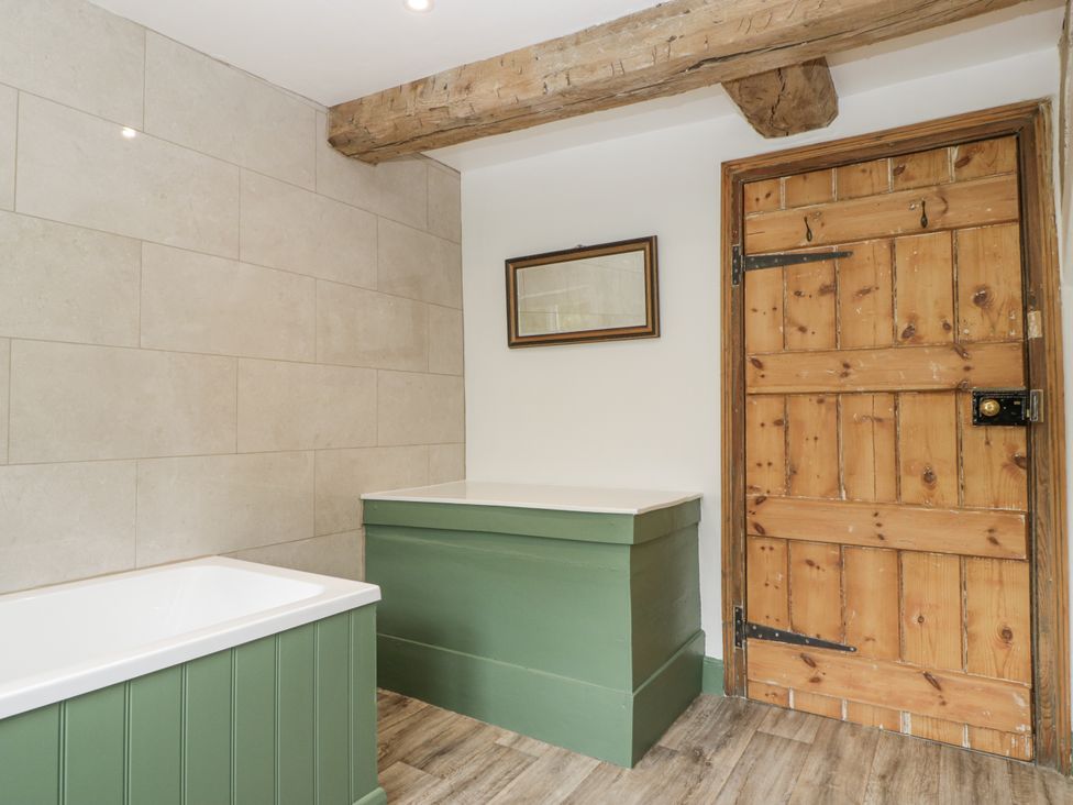 A bathroom with a bathtub and wooden features at Evenjobb Court Farmhouse Evenjobb near Presteigne