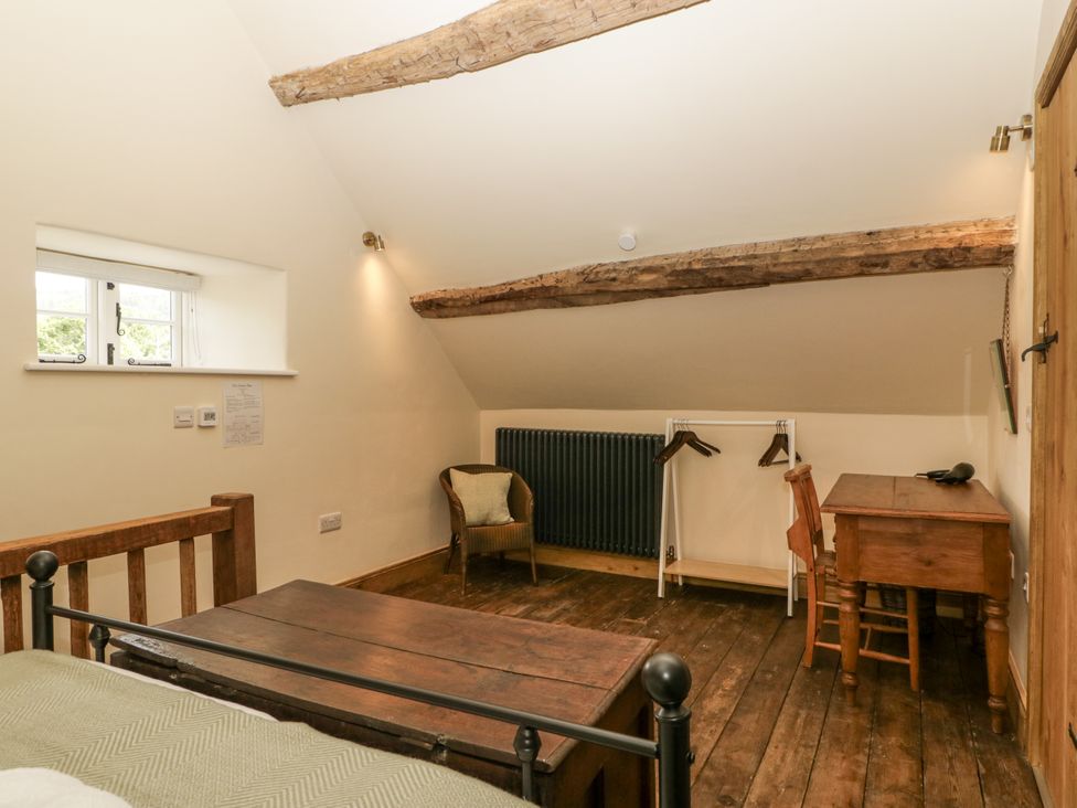 A bedroom with a bed, desk, and chair at Evenjobb Court Farmhouse near Presteigne