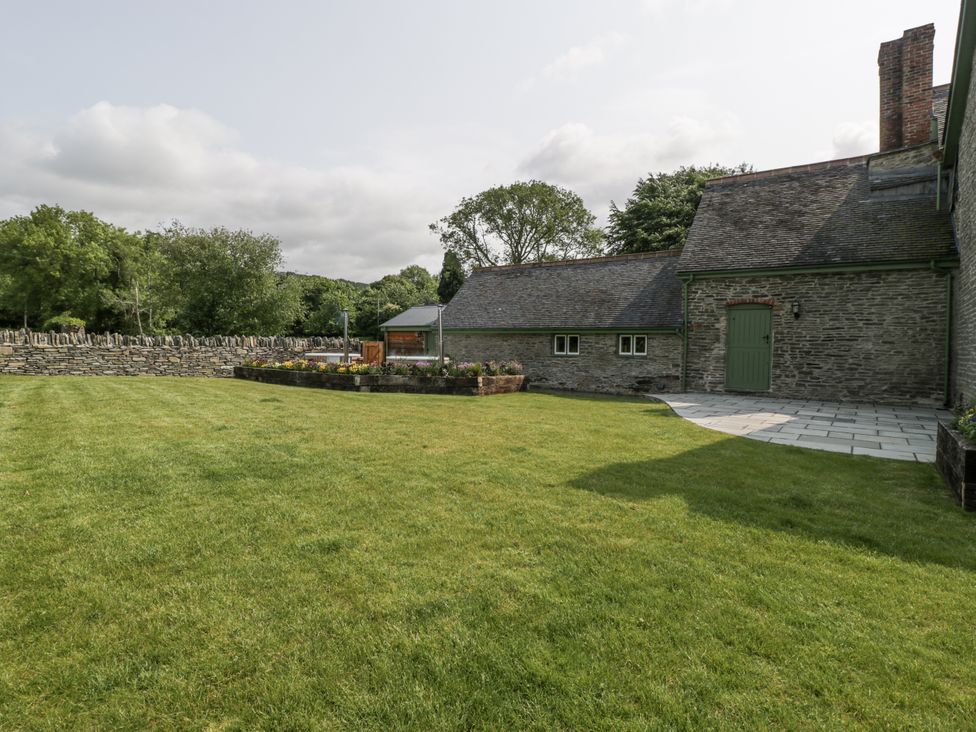 A garden with a house and stone wall at Evenjobb Court Farmhouse in Evenjobb near Presteigne