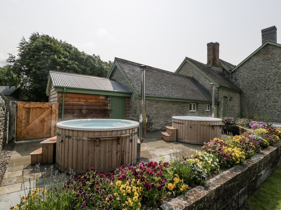 An outdoor area with hot tubs and flowers at Evenjobb Court Farmhouse in Evenjobb near Presteigne