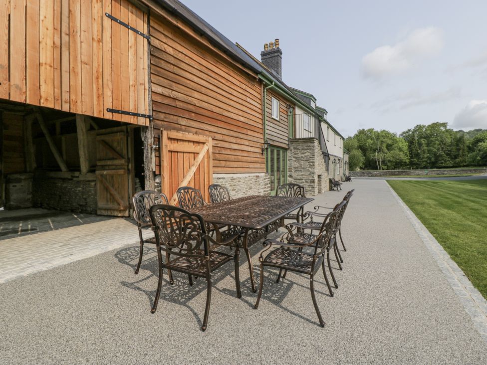 An outdoor dining table and chairs near a wooden barn at Evenjobb Court Farmhouse Evenjobb near Presteigne