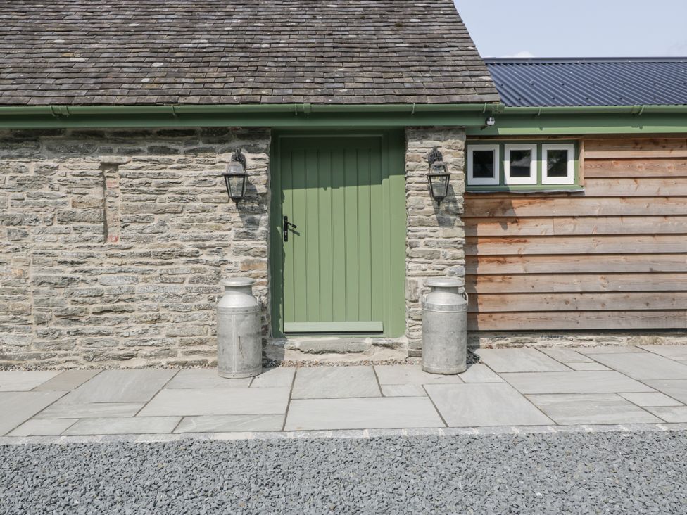 An outdoor entrance with a green door and milk cans at Evenjobb Court Farmhouse Evenjobb near Presteigne