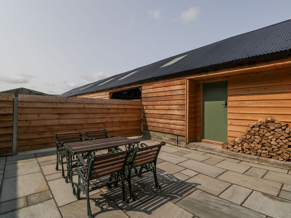 An outdoor patio with a table and chairs at Evenjobb Court Farmhouse near Presteigne