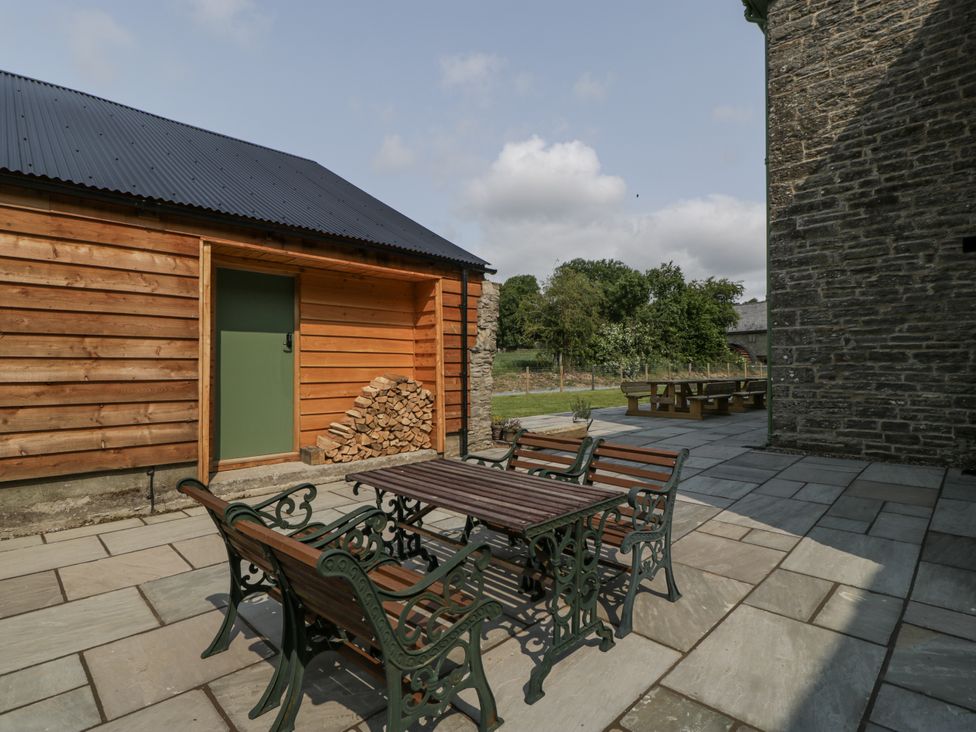An outdoor area with a wooden building and patio furniture at Evenjobb Court Farmhouse near Presteigne