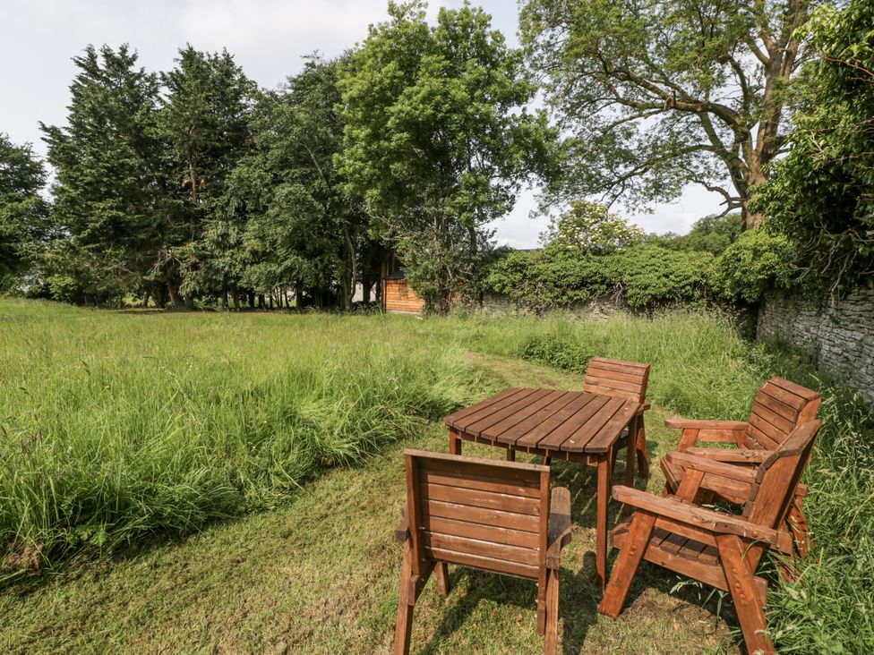 A garden with wooden furniture and grass at Evenjobb Court Farmhouse near Presteigne
