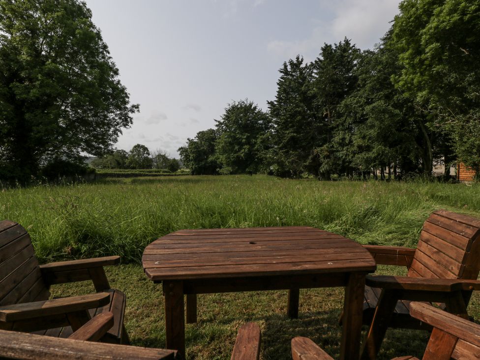 A garden with a wooden table and chairs at Evenjobb Court Farmhouse Evenjobb near Presteigne