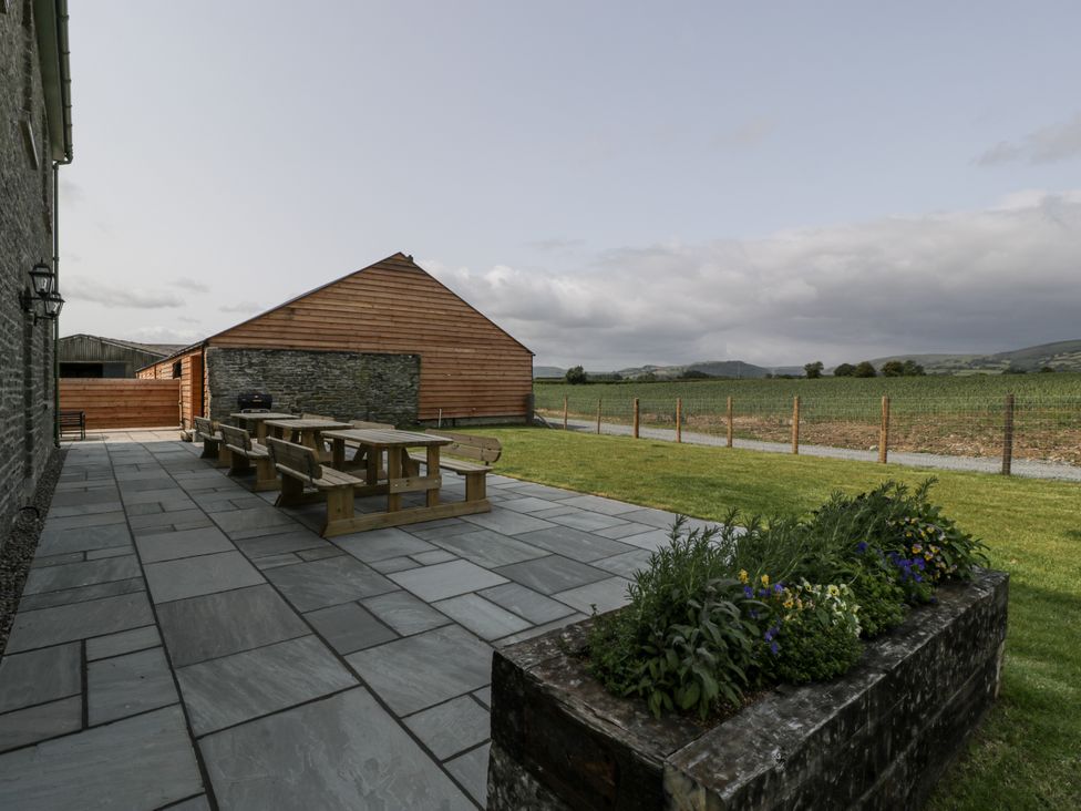 An outdoor area with a table and benches at Evenjobb Court Farmhouse near Presteigne