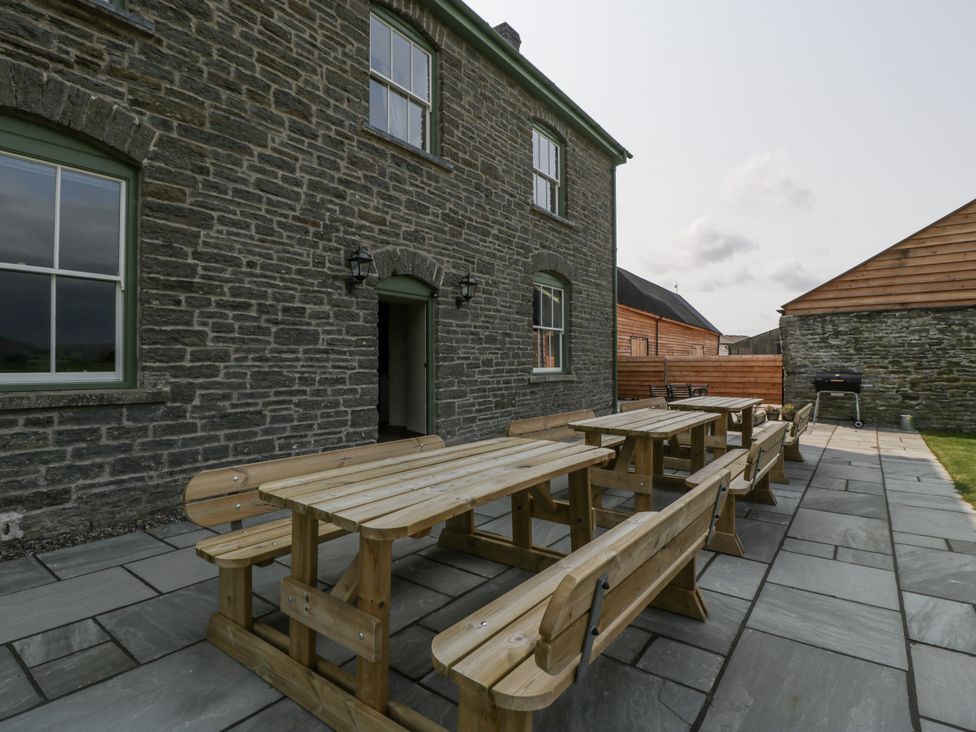 An outdoor area with wooden tables and chairs at Evenjobb Court Farmhouse near Presteigne