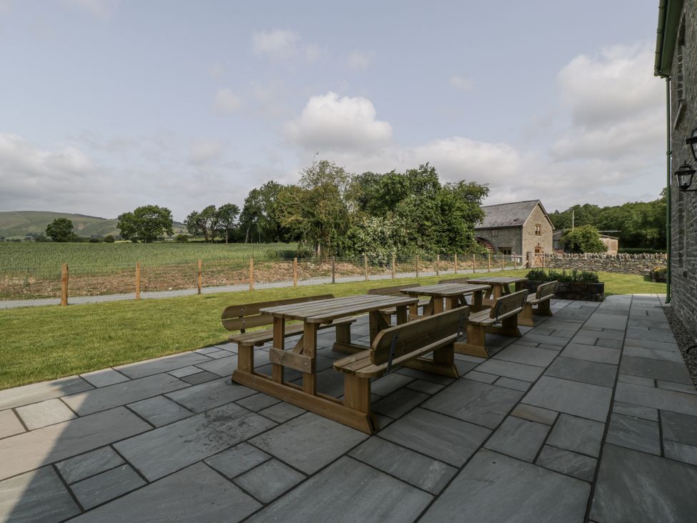 A patio area with a table and benches at Evenjobb Court Farmhouse near Presteigne