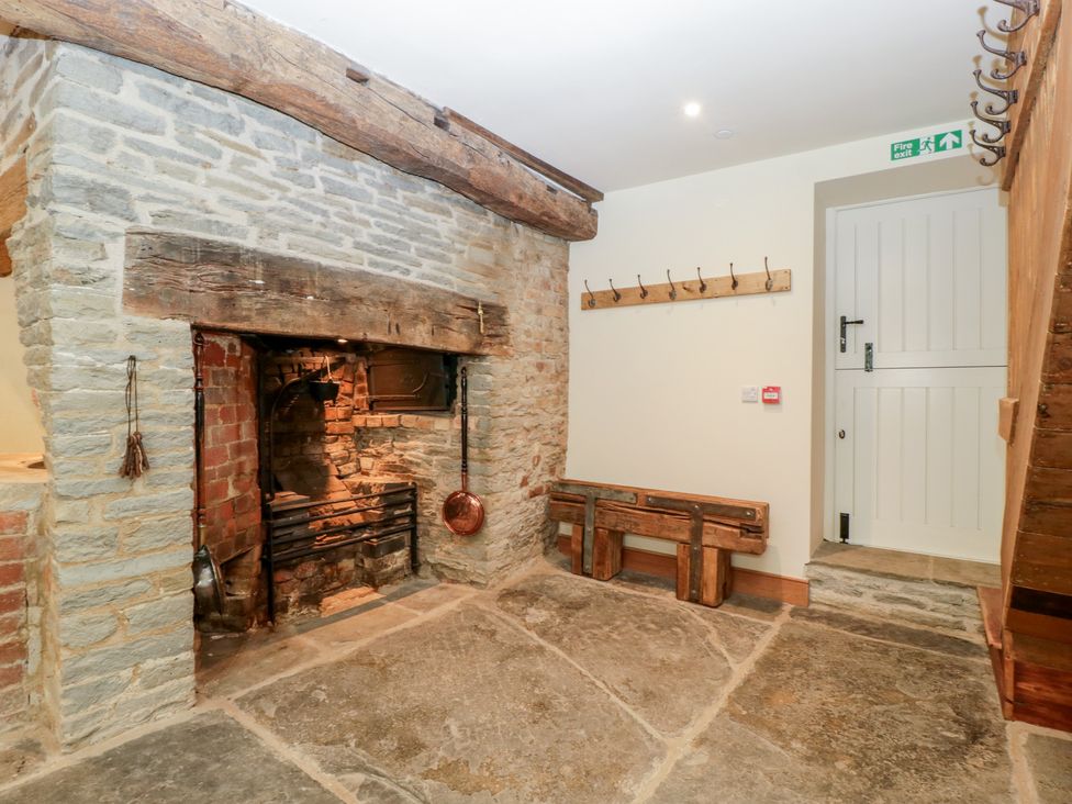 An entrance hall with a stone fireplace and wooden bench at Evenjobb Court Farmhouse near Presteigne