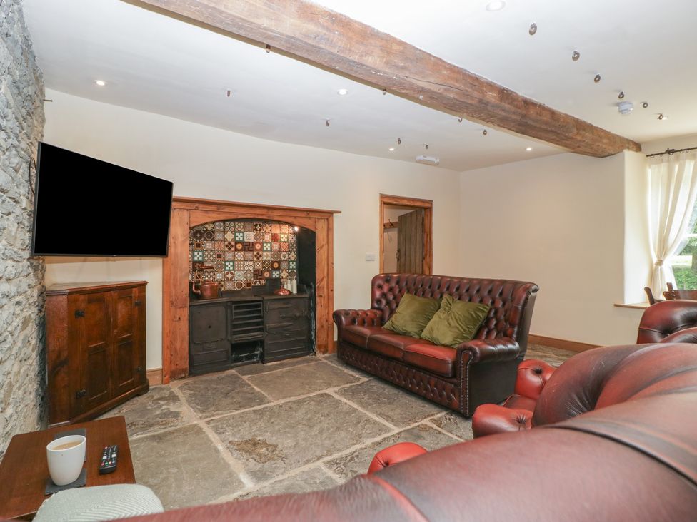 A living room with a television and a stone floor at Evenjobb Court Farmhouse near Presteigne
