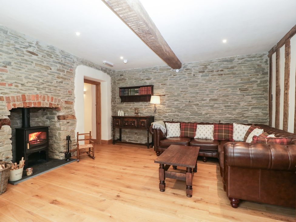 A living room with a fireplace and a sofa at Evenjobb Court Farmhouse Evenjobb near Presteigne