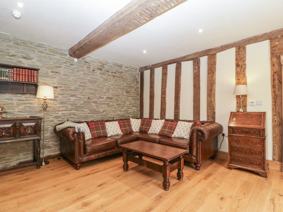 A living room with a leather sofa and wooden furniture at Evenjobb Court Farmhouse near Presteigne