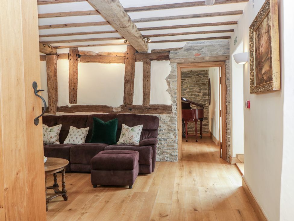 A living room with a sofa and ottoman at Evenjobb Court Farmhouse, Evenjobb near Presteigne