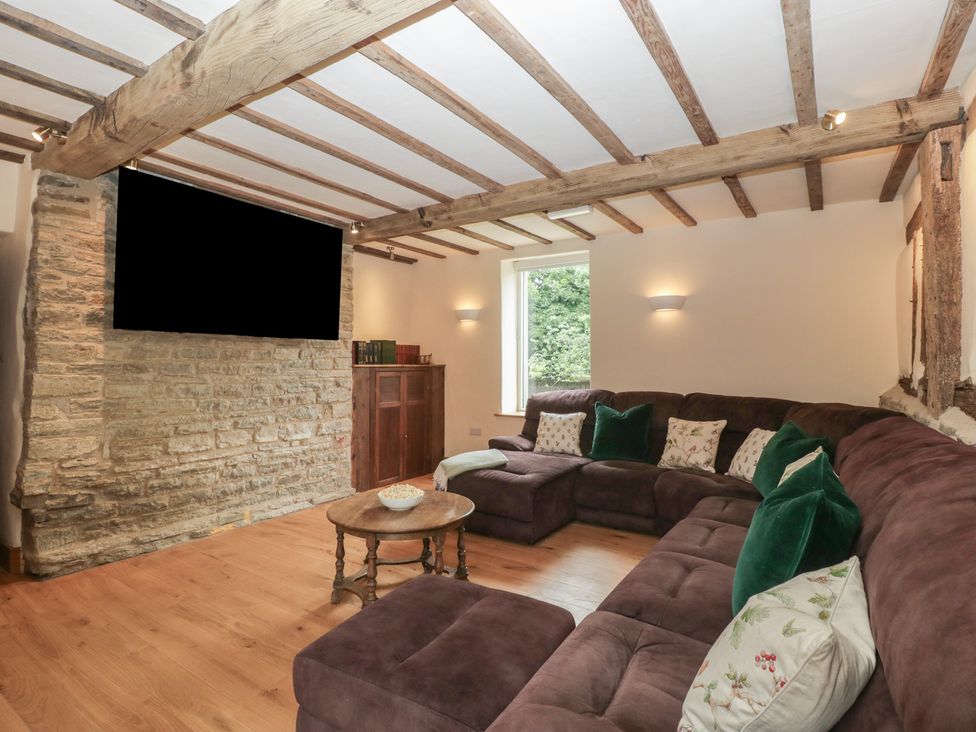 A living room with a sofa and television at Evenjobb Court Farmhouse near Presteigne