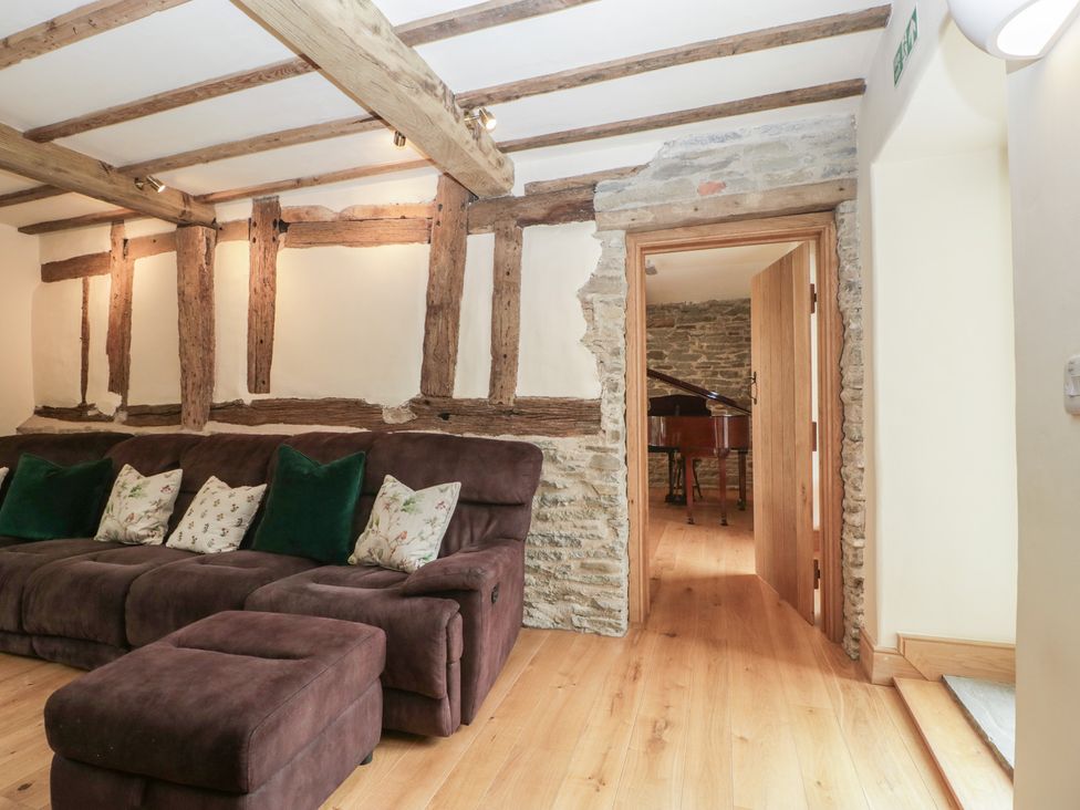 A living room with a sofa and door leading to another room at Evenjobb Court Farmhouse Evenjobb near Presteigne
