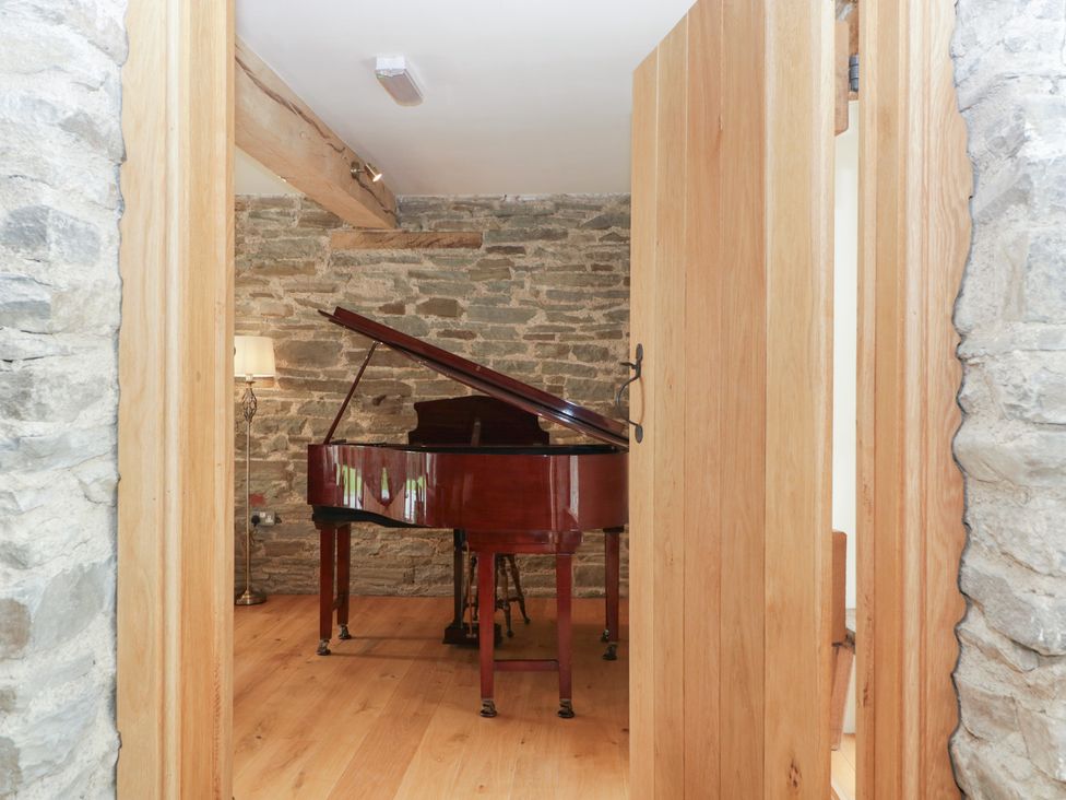 A music room with a piano and lamp at Evenjobb Court Farmhouse Evenjobb near Presteigne