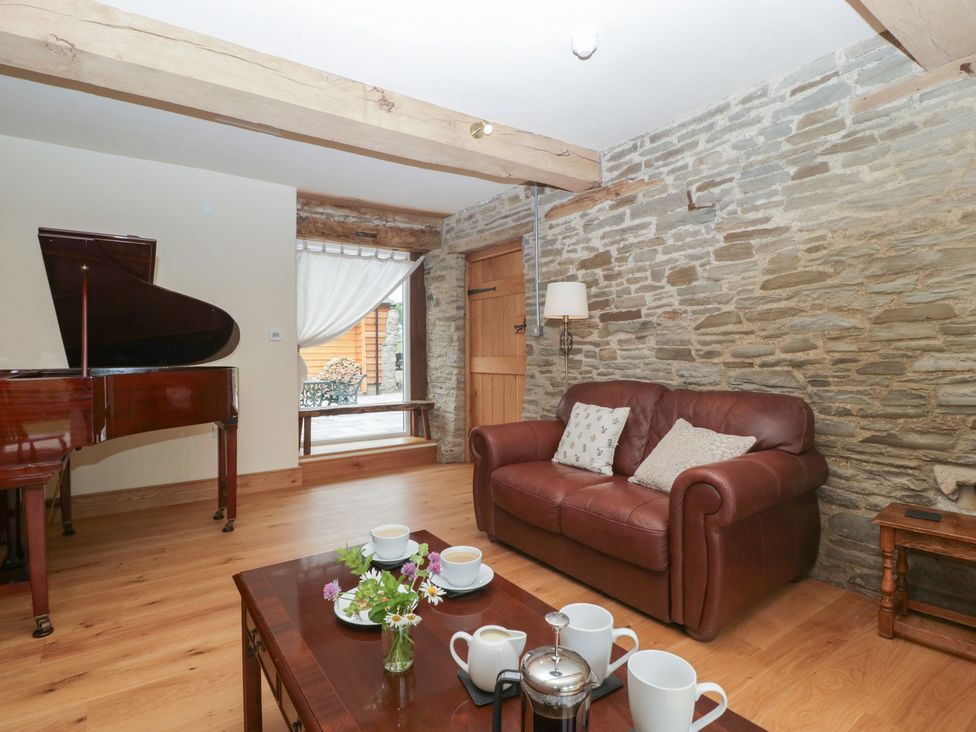 A living room with a piano and a sofa at Evenjobb Court Farmhouse Evenjobb near Presteigne