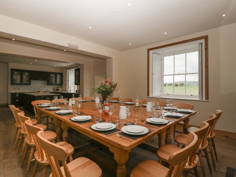 A dining room with a long table set for a meal at Evenjobb Court Farmhouse near Presteigne