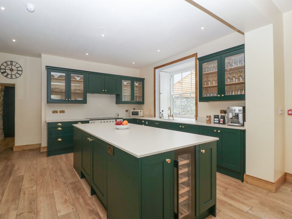 A kitchen with green cabinets and a central island at Evenjobb Court Farmhouse Evenjobb near Presteigne