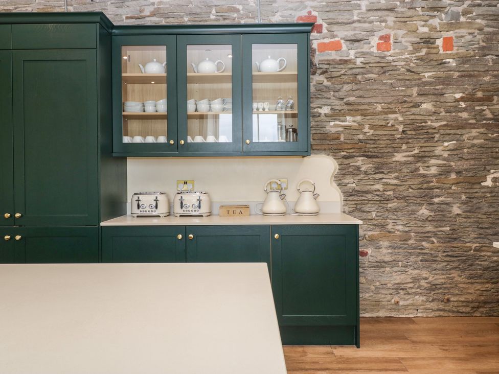 A kitchen with green cupboards and white mugs at Evenjobb Court Farmhouse Evenjobb near Presteigne