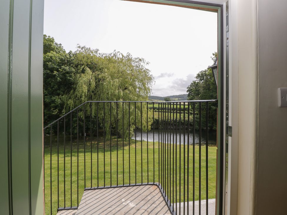 A view from a balcony overlooking a river and greenery at Evenjobb Court Farmhouse Evenjobb near Presteigne