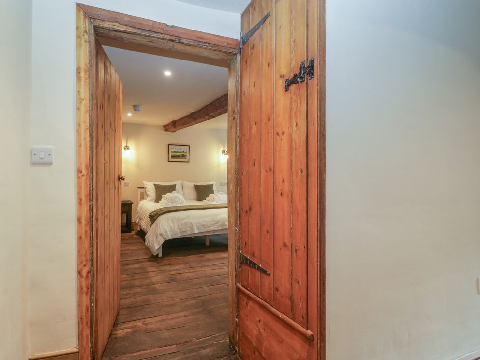A bedroom with a wooden door leading to a bed at Evenjobb Court Farmhouse Evenjobb near Presteigne
