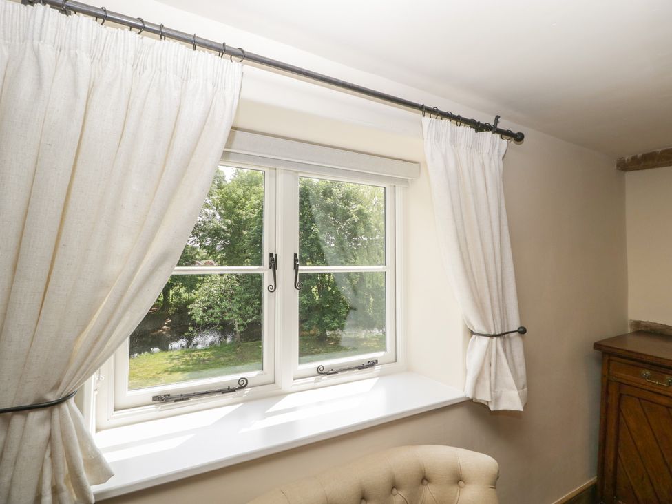 A window with curtains overlooking greenery at Evenjobb Court Farmhouse Evenjobb near Presteigne