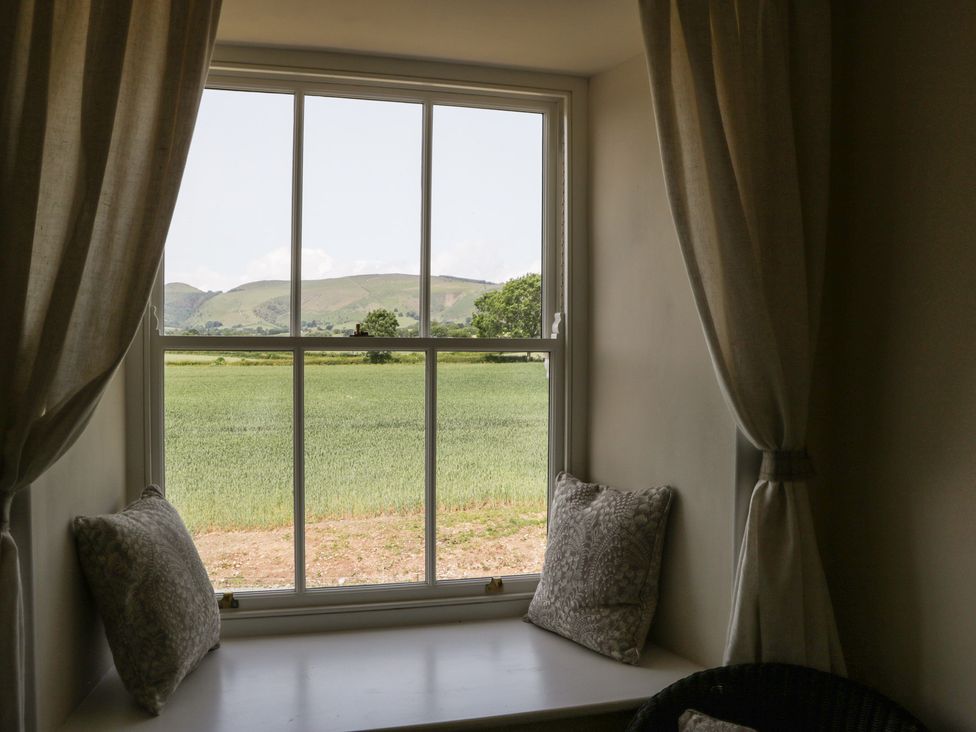 A window with a view of a field and hills at Evenjobb Court Farmhouse near Presteigne