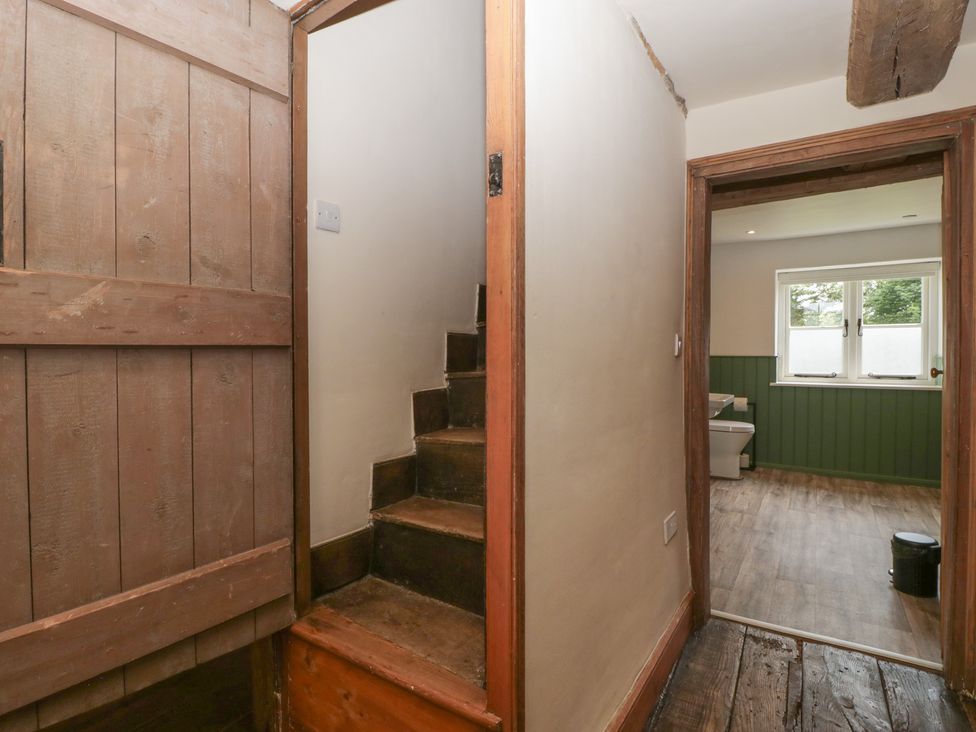 A hallway with a staircase and wooden door at Evenjobb Court Farmhouse Evenjobb near Presteigne